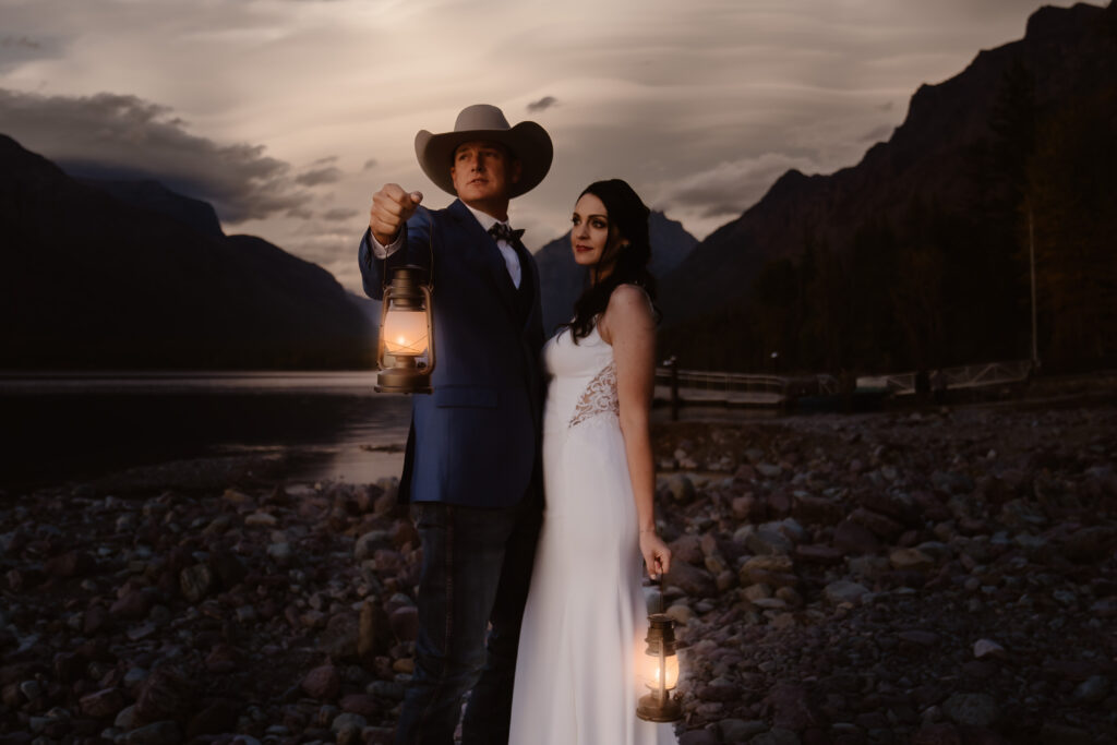 Styled shoot photo. Couple with lanterns on a rocky beach in front of mountains.