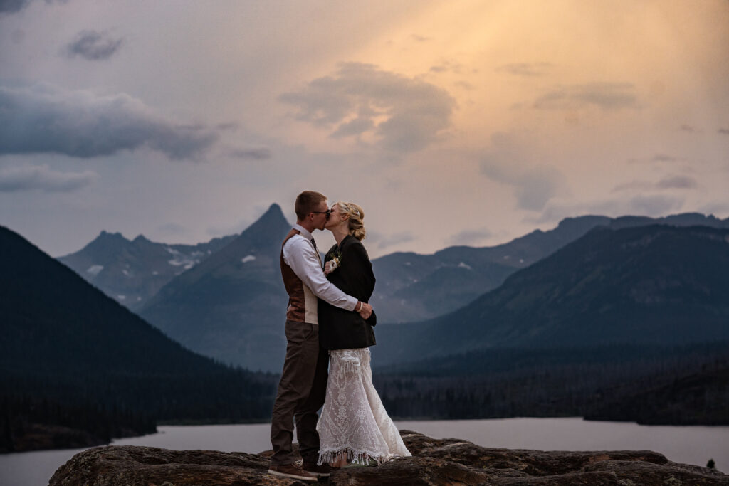 bride and groom kissing with mountains and sunset